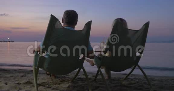 成熟的情侣在海滩上放松喝着鸡尾酒视频的预览图