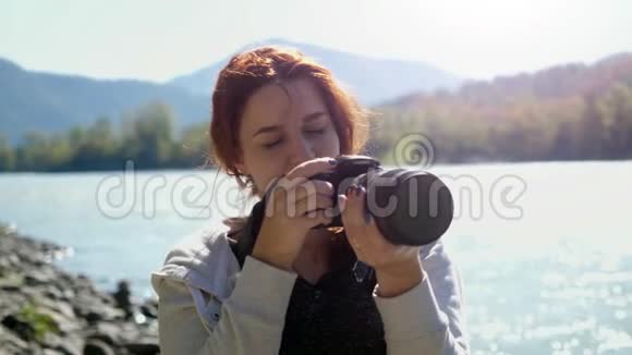 美丽的女人与红色头发摄影师拍照使用专业相机户外远足女性徒步旅行者视频的预览图