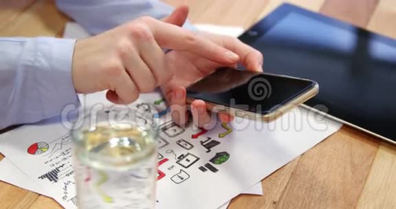 女商人在桌子上使用手机桌子上有图表和数字平板电脑视频的预览图