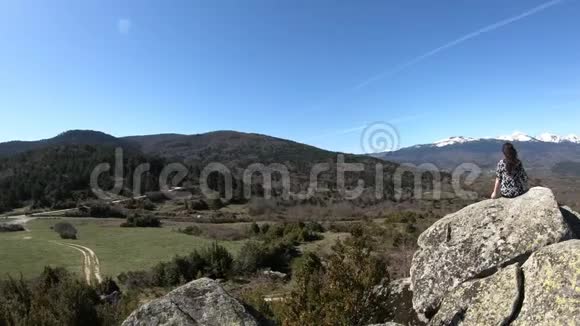 法国一个年轻女子独自坐在一块岩石上观察比利牛斯山脉视频的预览图