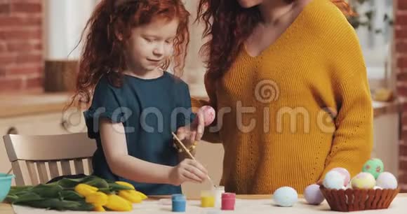 复活节快乐妈妈教女儿画鸡蛋为复活节做准备的幸福家庭小女孩戴着兔耳朵视频的预览图