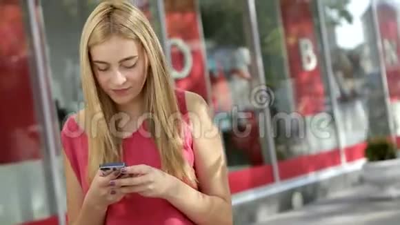 可爱的金发女郎在街上和朋友用电话聊天视频的预览图