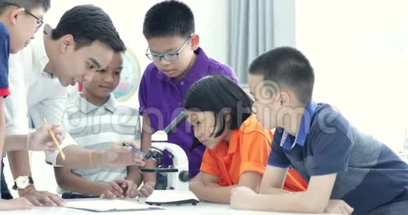 亚洲教师扩大到生物课学生与显微镜视频的预览图