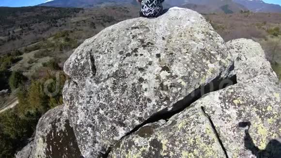 法国一个年轻女子独自坐在一块岩石上观察比利牛斯山脉视频的预览图