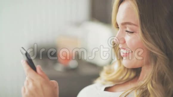 一个在轻床上用智能手机输入信息的漂亮女人视频的预览图