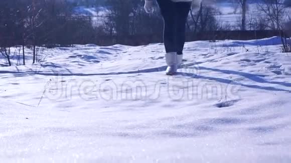 穿着银色冬靴的女孩在阳光明媚的雪地上行走放大慢动作视频视频的预览图