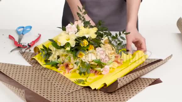 花匠在花束周围做包装纸白色的关门视频的预览图