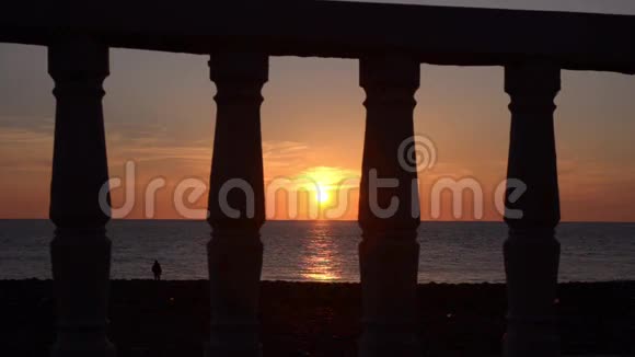透过栏杆观看海滨平静的大海和美丽的日落视频的预览图