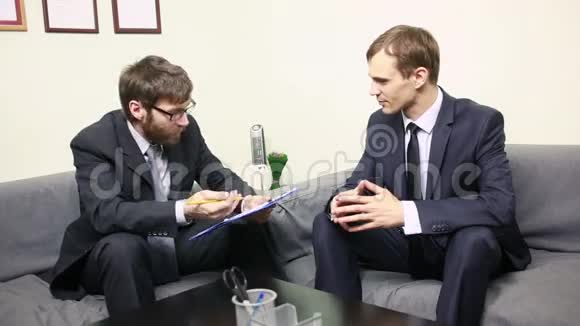 经理在他的办公室面试一位男性申请人两个西装革履的男人视频的预览图