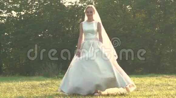 漂亮的新娘穿着白色连衣裙在田野里旋转慢慢地视频的预览图