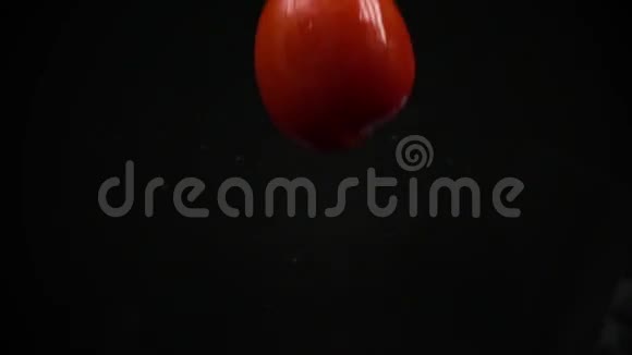 切下红色番茄落在黑色浇水表面超级慢动作镜头视频的预览图