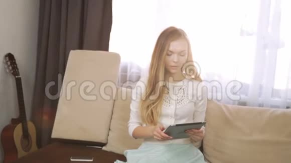家庭科技和互联网概念微笑的女人坐在沙发上家里有平板电脑喝白茶视频的预览图