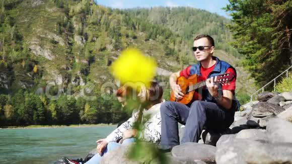 一群快乐的朋友在海边玩吉他在山河旁边的夏天3840x21604k视频的预览图