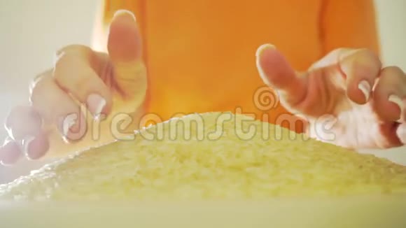 穿着橙色衣服的女人用手舀米堆慢动作视频视频的预览图