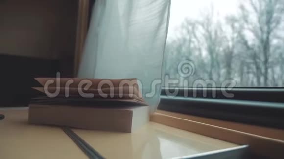 这本书在火车上的桌子上铁路旅行概念教练火车旅行从窗户看到美丽的景色视频的预览图