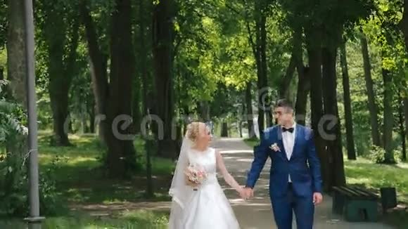 在公园的小巷里散步的新婚夫妇视频的预览图