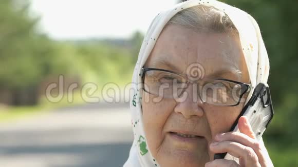 微笑的老妇人在户外使用智能手机聊天视频的预览图