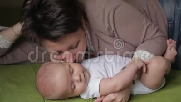 年轻漂亮的妈妈用爱亲吻她的小宝宝视频的预览图