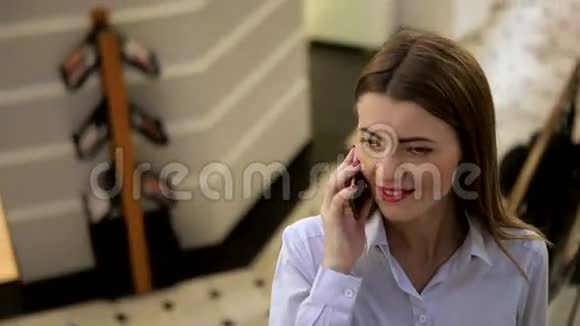 一个红唇红指甲油的女孩正在商场里用手机聊天视频的预览图