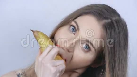 一个漂亮的女孩在工作室里吃一个梨视频的预览图