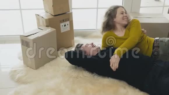 新婚夫妇幸福地躺在新房子的地毯上玩得开心视频的预览图