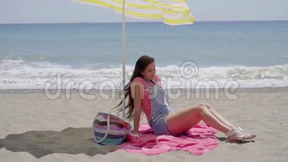 在海滩上坐在毯子上的女人视频的预览图