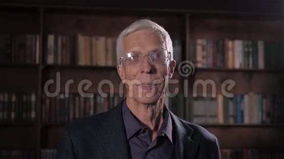 图书馆里一位相貌英俊的老人身穿西装头戴灰色头发戴着眼镜笑容满面心情愉快视频的预览图