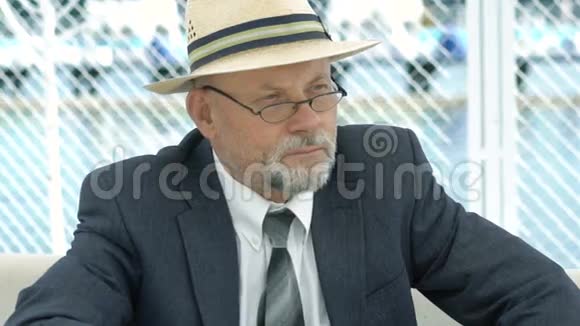 一位戴着帽子西装和眼镜的老人的肖像向一边看视频的预览图