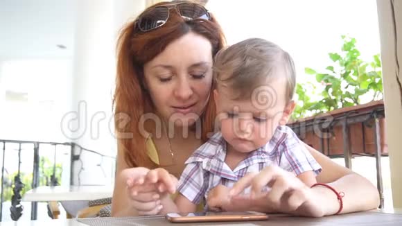 一个和妈妈在一起的小男孩用智能手机上网视频的预览图