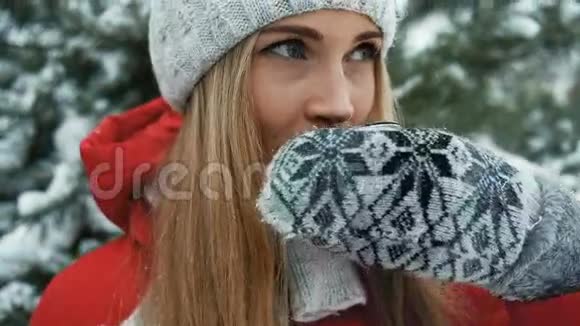 迷人的金发女郎在冬季景色的背景下喝着热茶视频的预览图