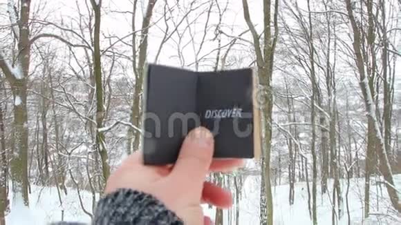 发现或旅程概念手拿着一本有铭文的书冬季森林的背景视频的预览图