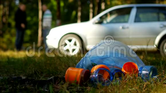 一包带塑料瓶的垃圾躺在大自然上背景中有一辆车人们都是视频的预览图