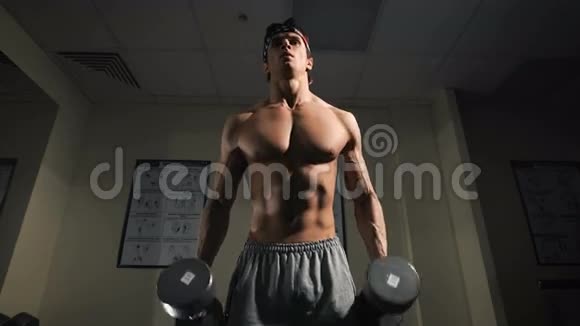 强壮的男人健身者在健身房用哑铃锻炼视频的预览图