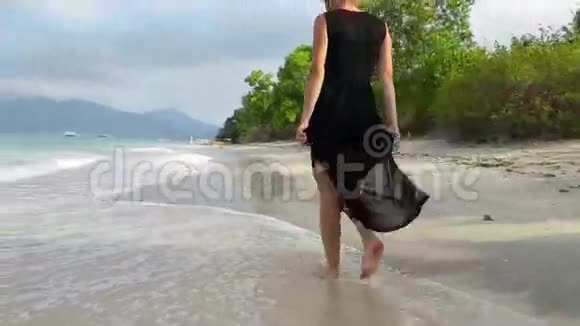 穿着黑色雪纺连衣裙的女人走在海边视频的预览图