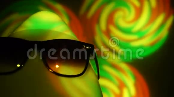戴墨镜的光头男在五颜六色的聚光灯下视频的预览图