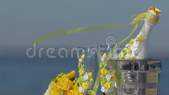 冰桶中的香槟瓶两个玻璃杯和海滩上的婚礼装饰视频的预览图