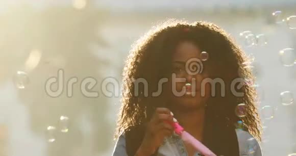 美国黑人女孩的横向肖像她的卷发吹着肥皂泡视频的预览图