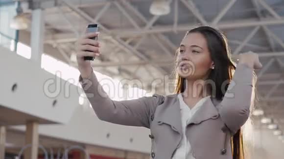 一个美丽的女孩在机场航站楼自拍商场里带电话的年轻女商人视频的预览图