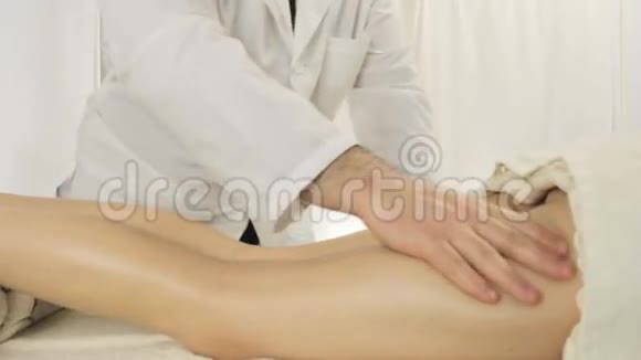 按摩师医生带领一双手覆盖整条腿放松双脚按摩沙龙中的年轻女性视频的预览图