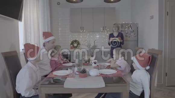 一家人庆祝新年厨房餐桌父亲儿子女儿微笑的母亲正在供应晚餐视频的预览图