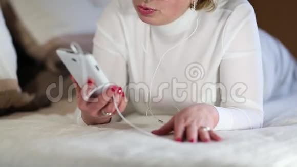 带着白色智能手机的老妇人躺在床上视频的预览图
