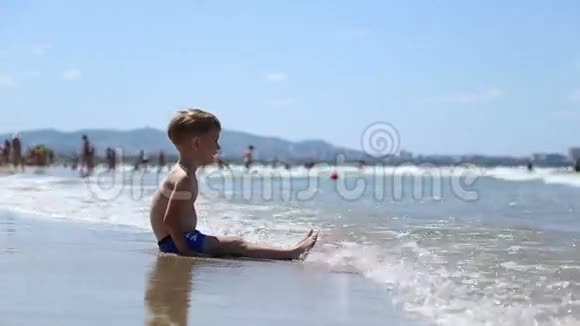 一个小男孩坐在水里的沙子上视频的预览图