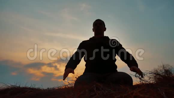 一位在日落阳光下冥想的男僧的剪影佛教祈祷日落时生活方式健康视频的预览图