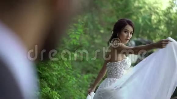 新娘在瀑布附近盘旋挥舞着礼服视频的预览图