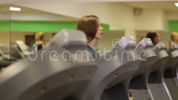 女人在健身俱乐部的跑步机上跑步视频的预览图