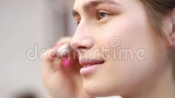 迷人的女人闭上眼睛微笑雌性的手拿着眼影和刷子女性手工制作视频的预览图