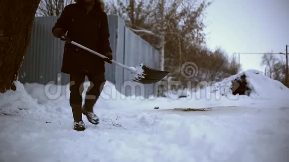 雪夜后工作在一个寒冷的雪天早晨一个拿着铲子把雪从他的院子里移走的人视频的预览图