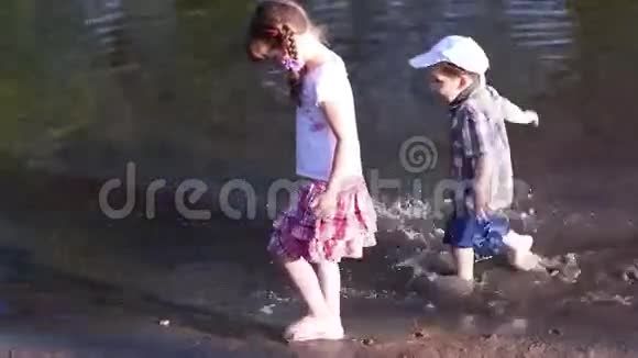 小男孩在水中奔跑女孩在池塘边散步视频的预览图