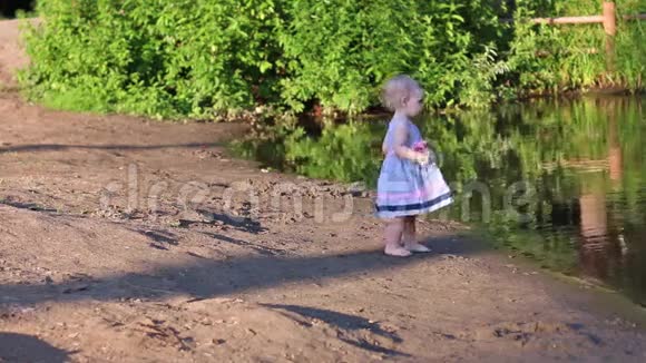 穿着裙子的小女孩在岸上散步视频的预览图