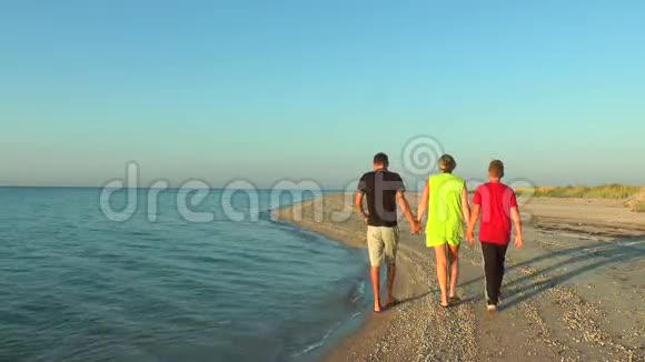 母亲和孩子在黎明时沿着海滨散步视频的预览图